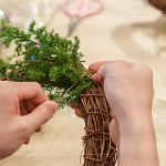 先以鐵絲穿過(guò)藤圈並收好，抓一把雪松，繞過(guò)後拉緊，再取一把雪松，在第一把根部接上，以此將雪松綁完。