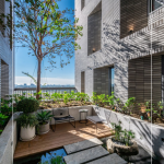 四季合院，每三層設(shè)計(jì)一處公共大露臺，從梯廳走入彷彿大家庭的合院(埕)，提供住戶們休憩及交誼空間，搭配四季主題的呼應(yīng)，此為七樓的夏季-種植小花紫薇與厚葉石斑木。