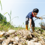從石縫中抽出韌性的橡膠圈，岸邊的垃圾也不可輕忽，可能會因?yàn)闈q潮後的潮水而沖刷到溪裡。